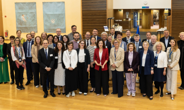 A large group of people stand in a hall, smiling at the camera
