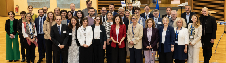 A large group of people stand in a hall, smiling at the camera