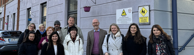 A group of people stand outside a school building